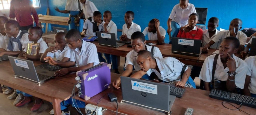 Busy classroom with students using laptops. A Jangala wifi box is in the foreground, providing internet to the school.